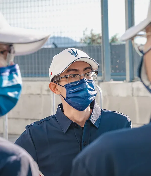 總教練 David 戴著白色帽子與口罩，在賽道活動現場說明